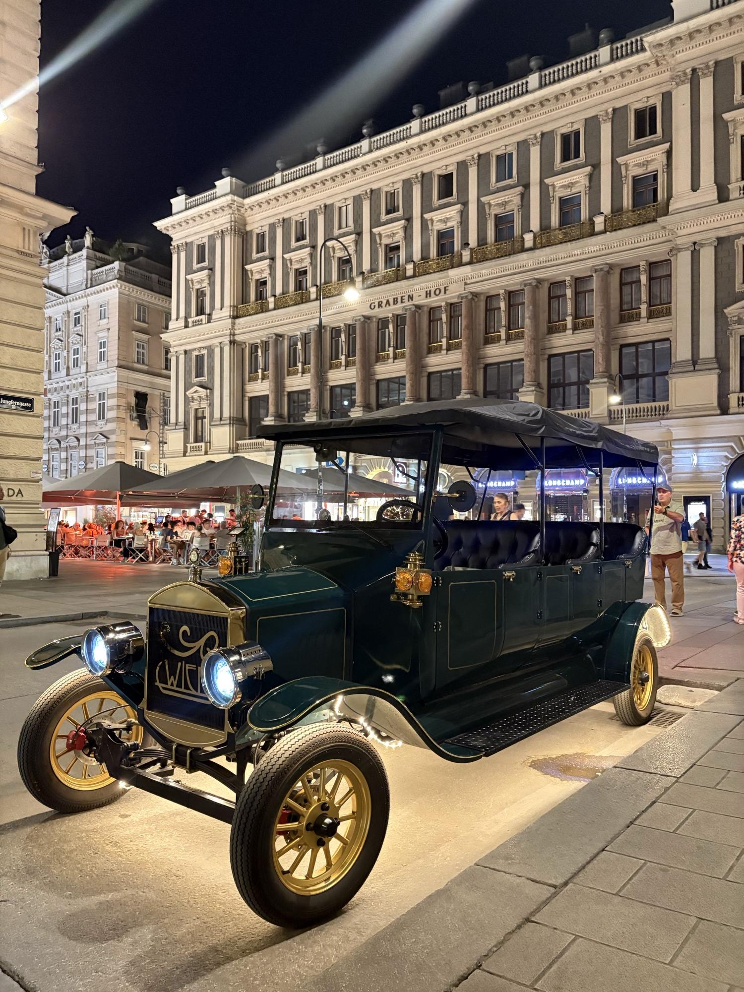 Dark green vintage EV on the Graben at night