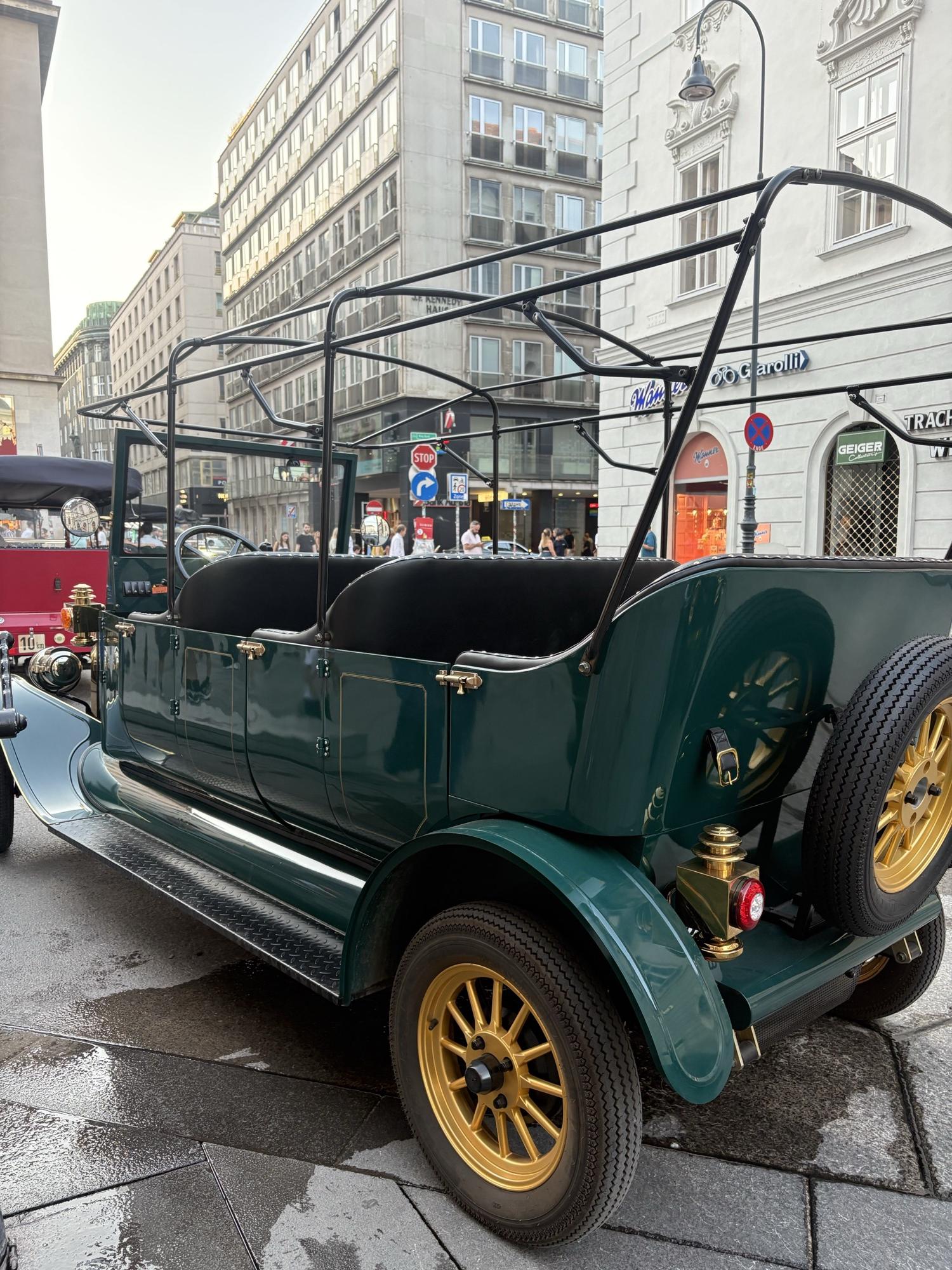 Full side profile of the dark green vintage electric tour vehicle near Stephansdom